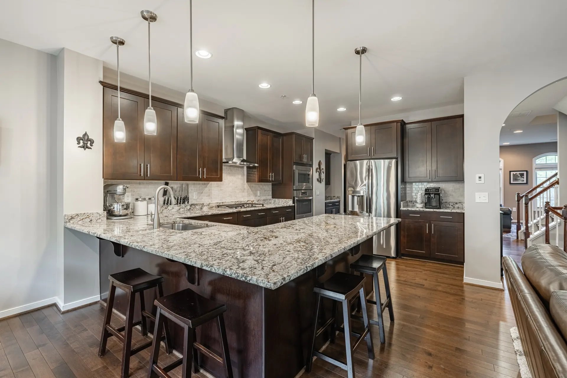 Kitchen with a large granite island, pendant lights and espresso cabinetry