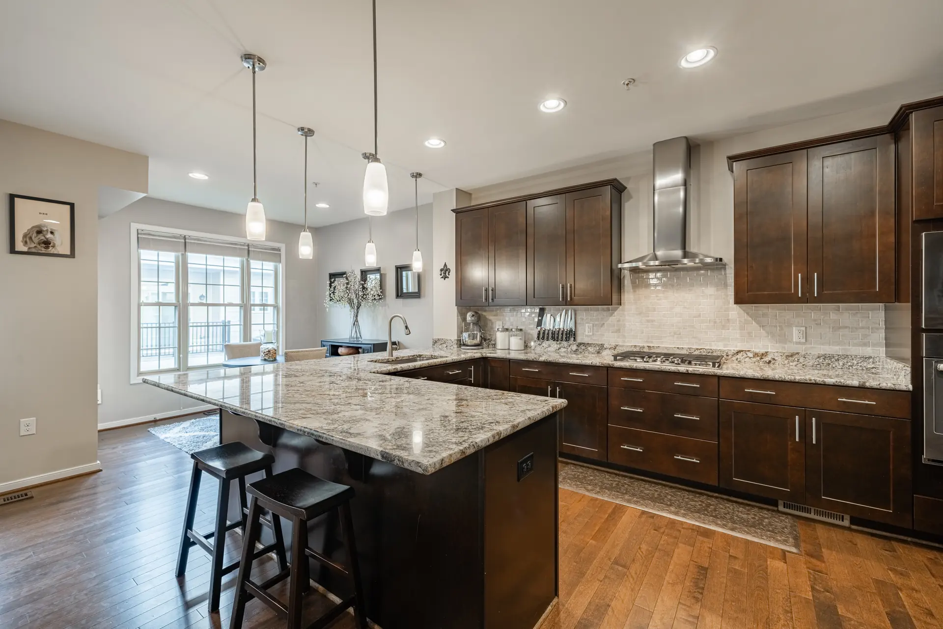 Wide view of the kitchen with stainless range hood and island seating