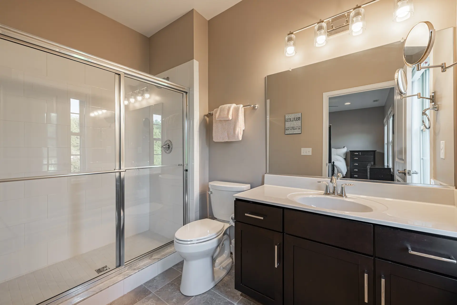 Full bath with glass-enclosed shower and dark vanity