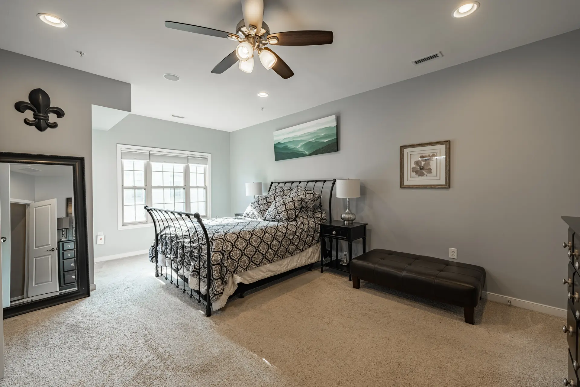 Primary bedroom with iron sleigh bed and ceiling fan