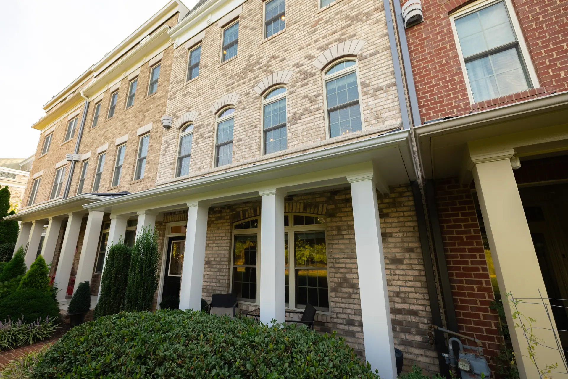 Brick facade and columned porches along the townhome row