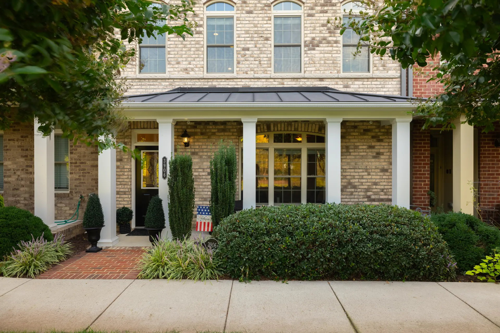 Covered front porch with columns and boxwood plantings