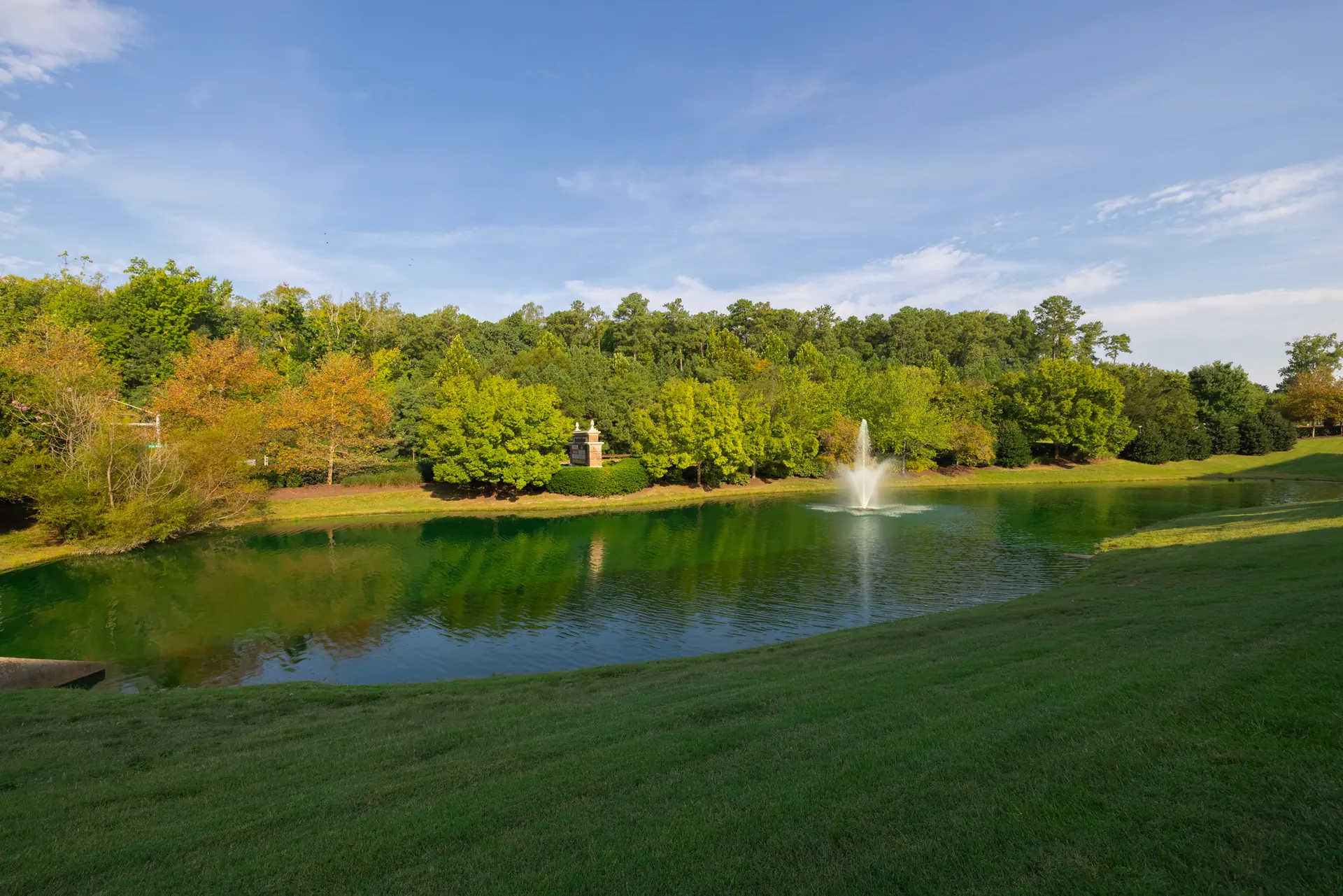 Community pond and fountain framed by mature trees
