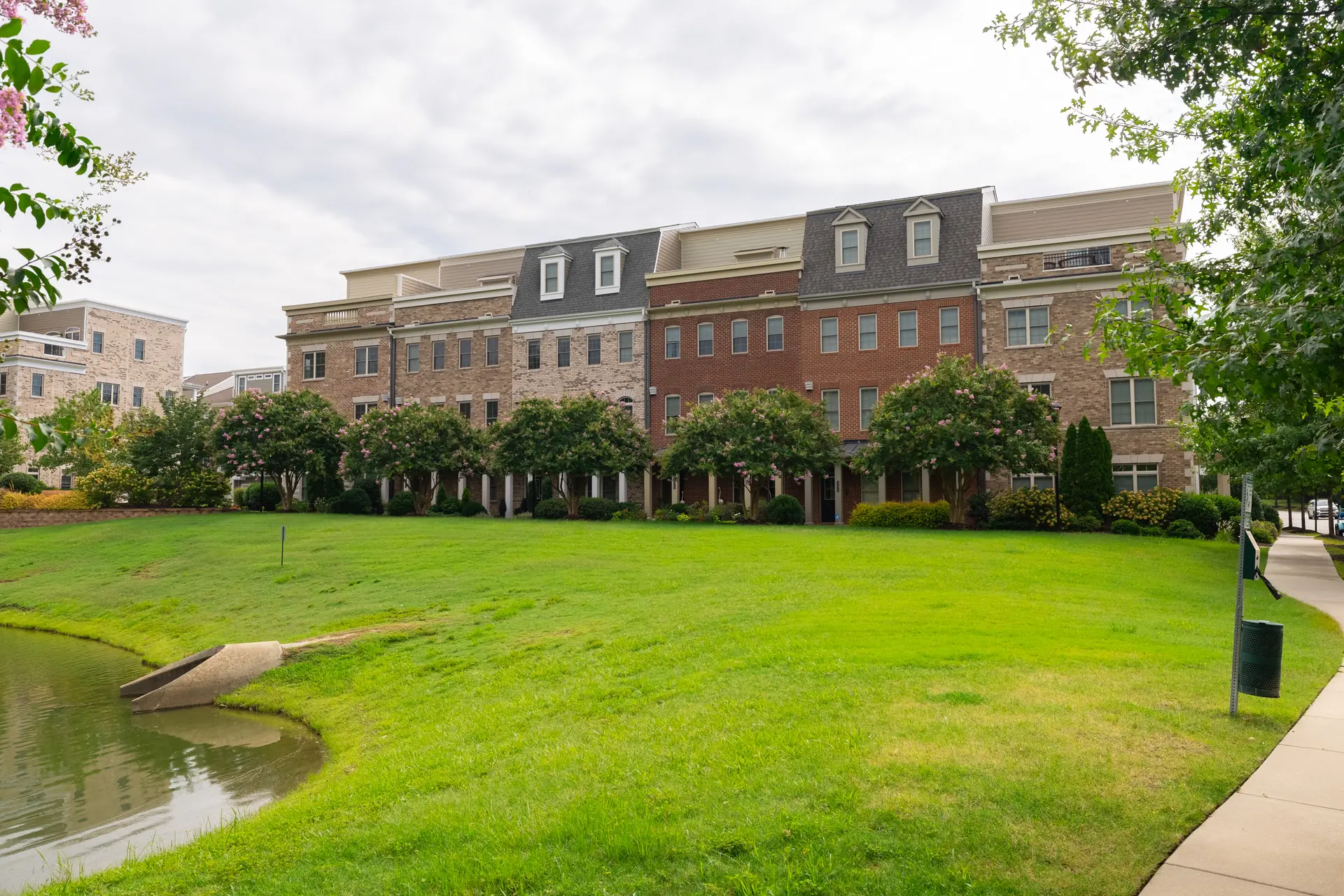 Open green and pond framed by the townhome row