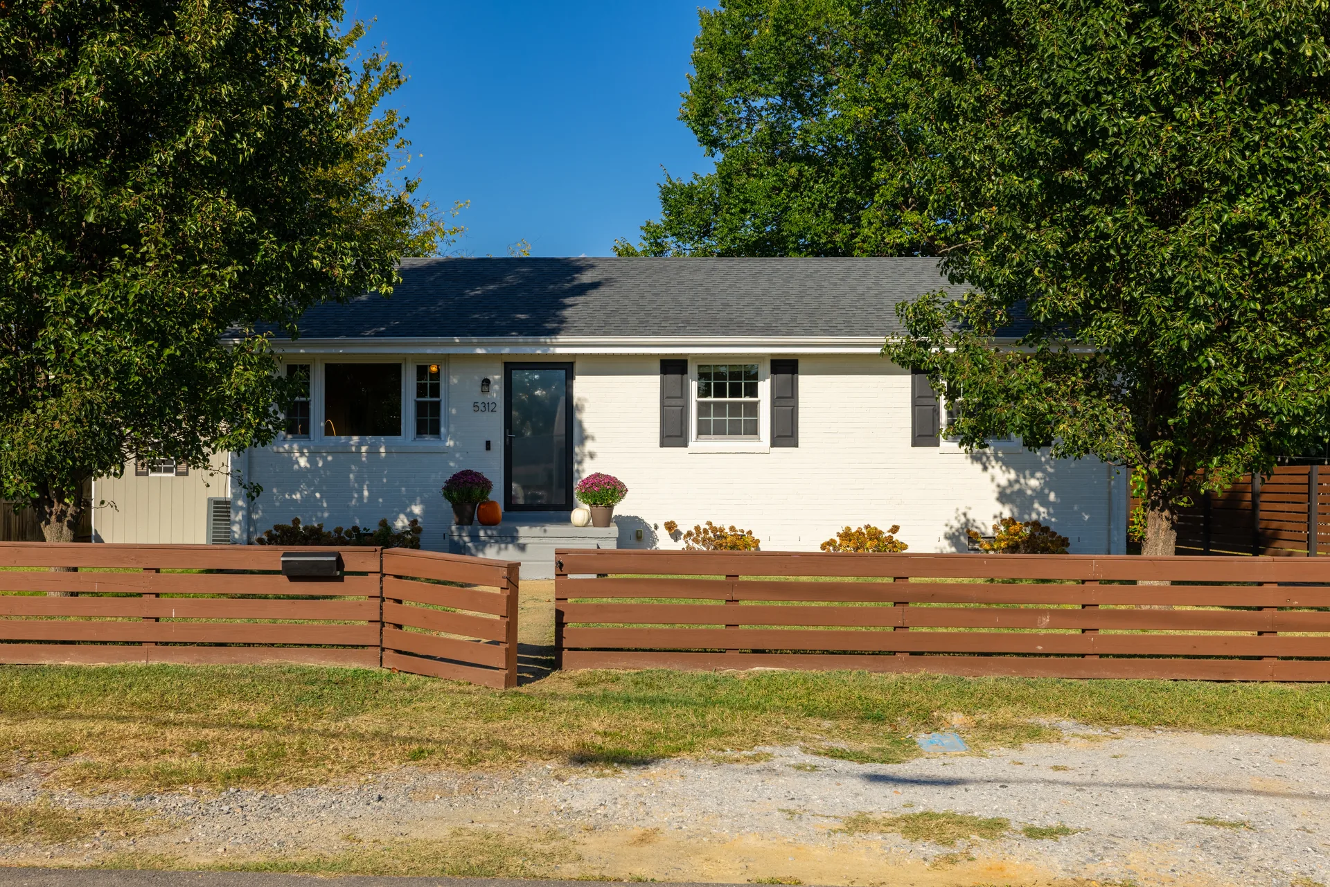 5312 Marian St &mdash; rear of the house with the horizontal wood fence and gravel drive