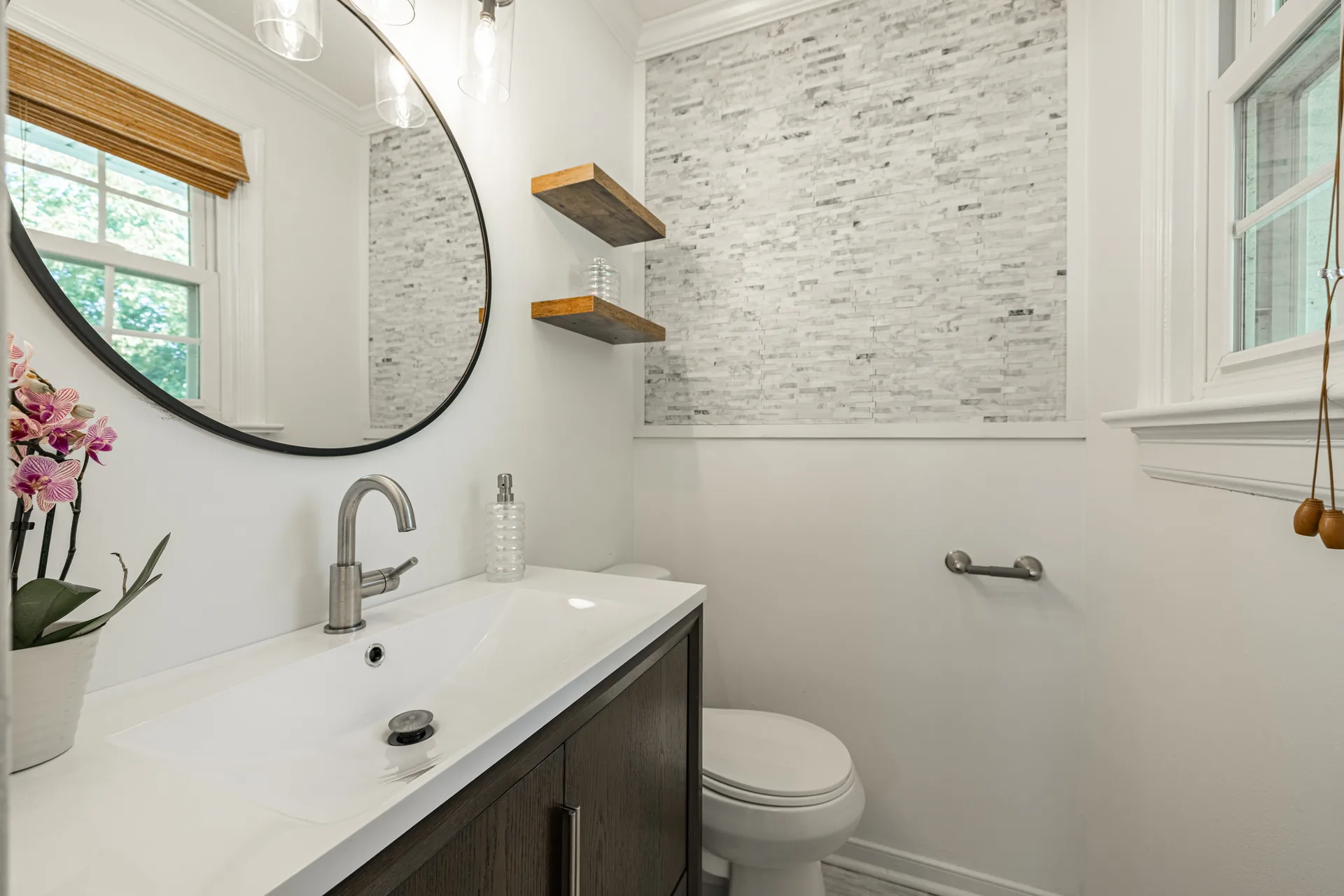 5312 Marian St &mdash; half bath with a quartz-topped vanity, round mirror and stacked-stone wall
