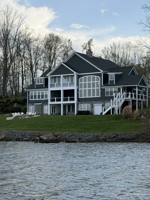 Shingle-style waterfront home with stone foundation and lawn running to the water in Lake Anna, Virginia